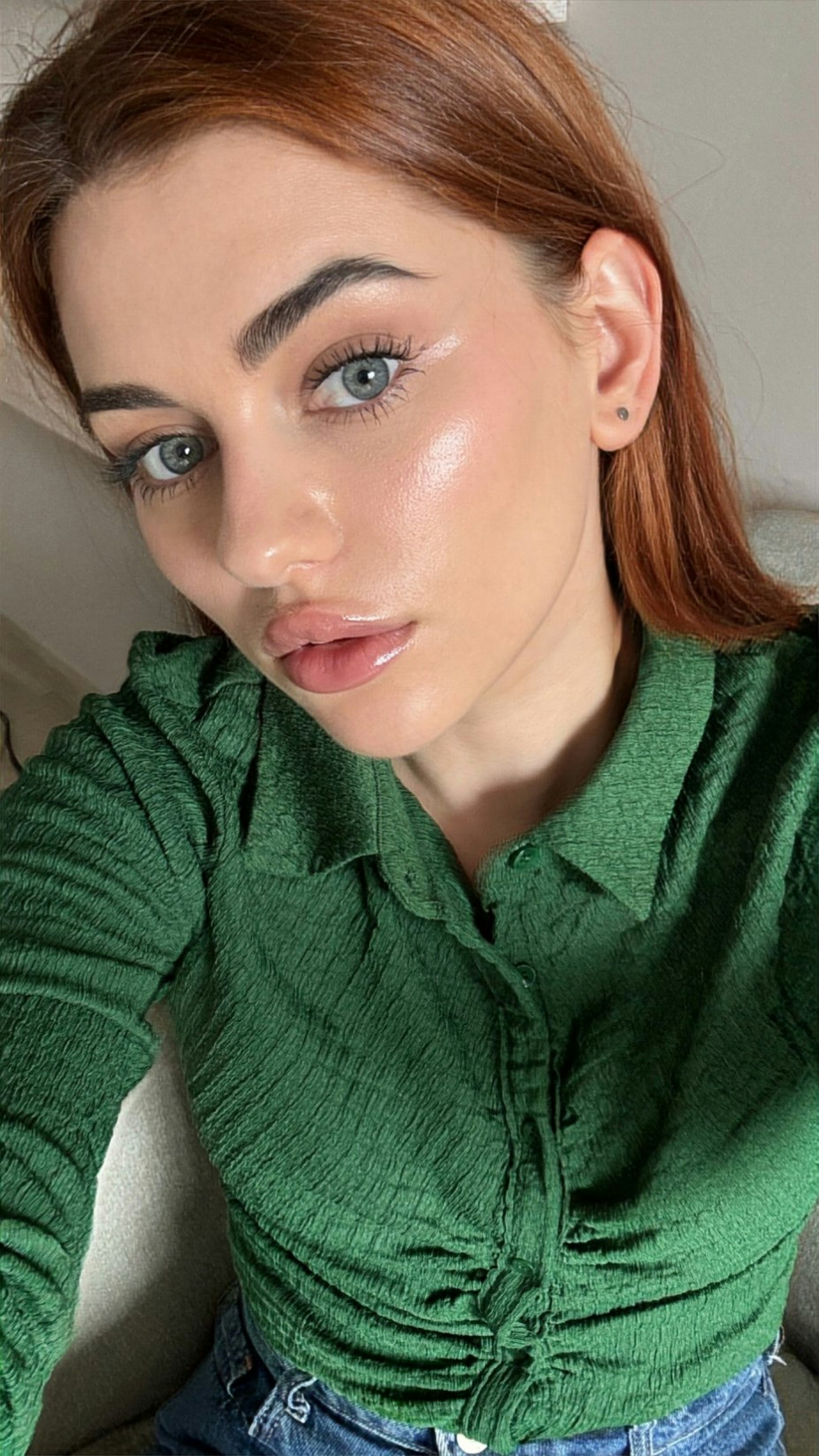 Woman with red hair wearing a green shirt and jeans.