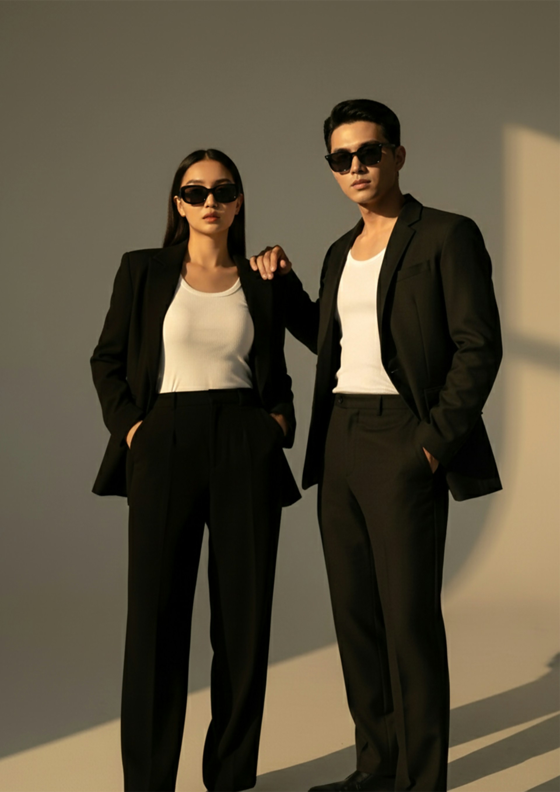 A man and woman in black suits and sunglasses.