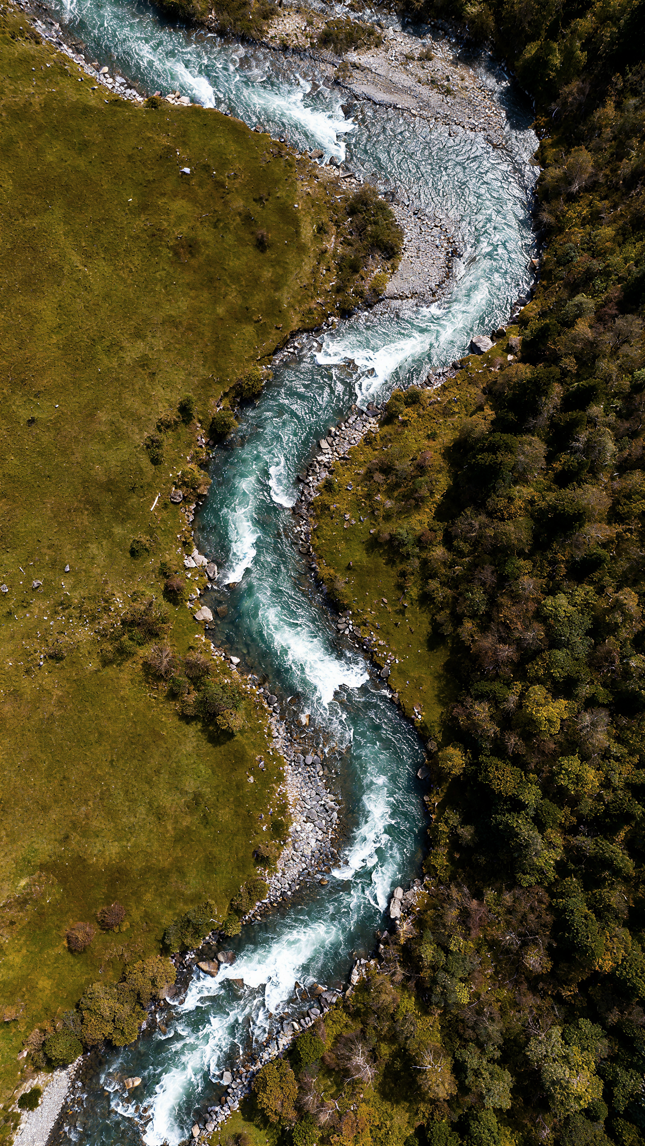 Luftaufnahme eines gewundenen Flusses, der durch die grüne Landschaft fließt.