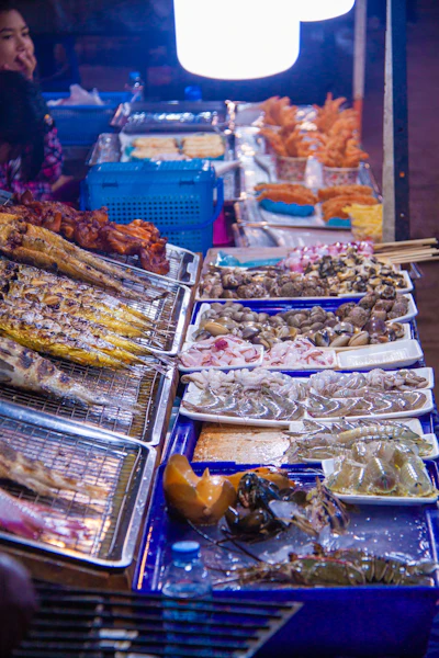 A street food stall grilling fish and seafood skewers, typical of an evening night market
