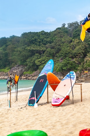 Surfboards and paddleboards on a sandy beach.
