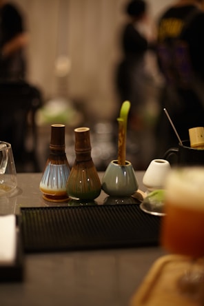Three ceramic vases with a plant and other objects.