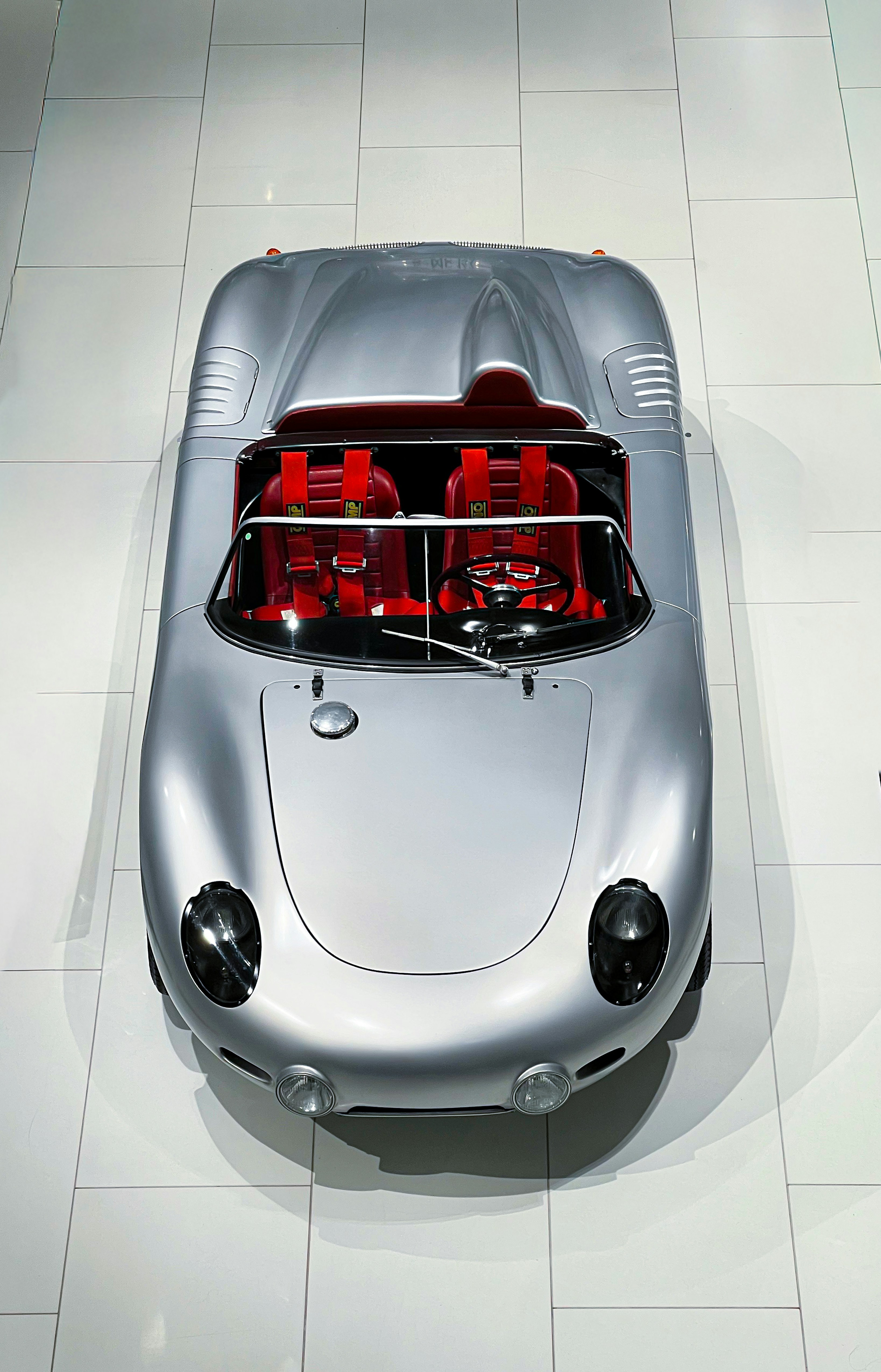 A vintage silver convertible sports car with red interior.