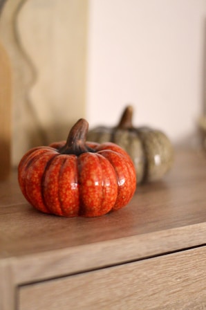 Two decorative pumpkins on a wooden surface.