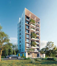 Modern apartment building with lush greenery and car.