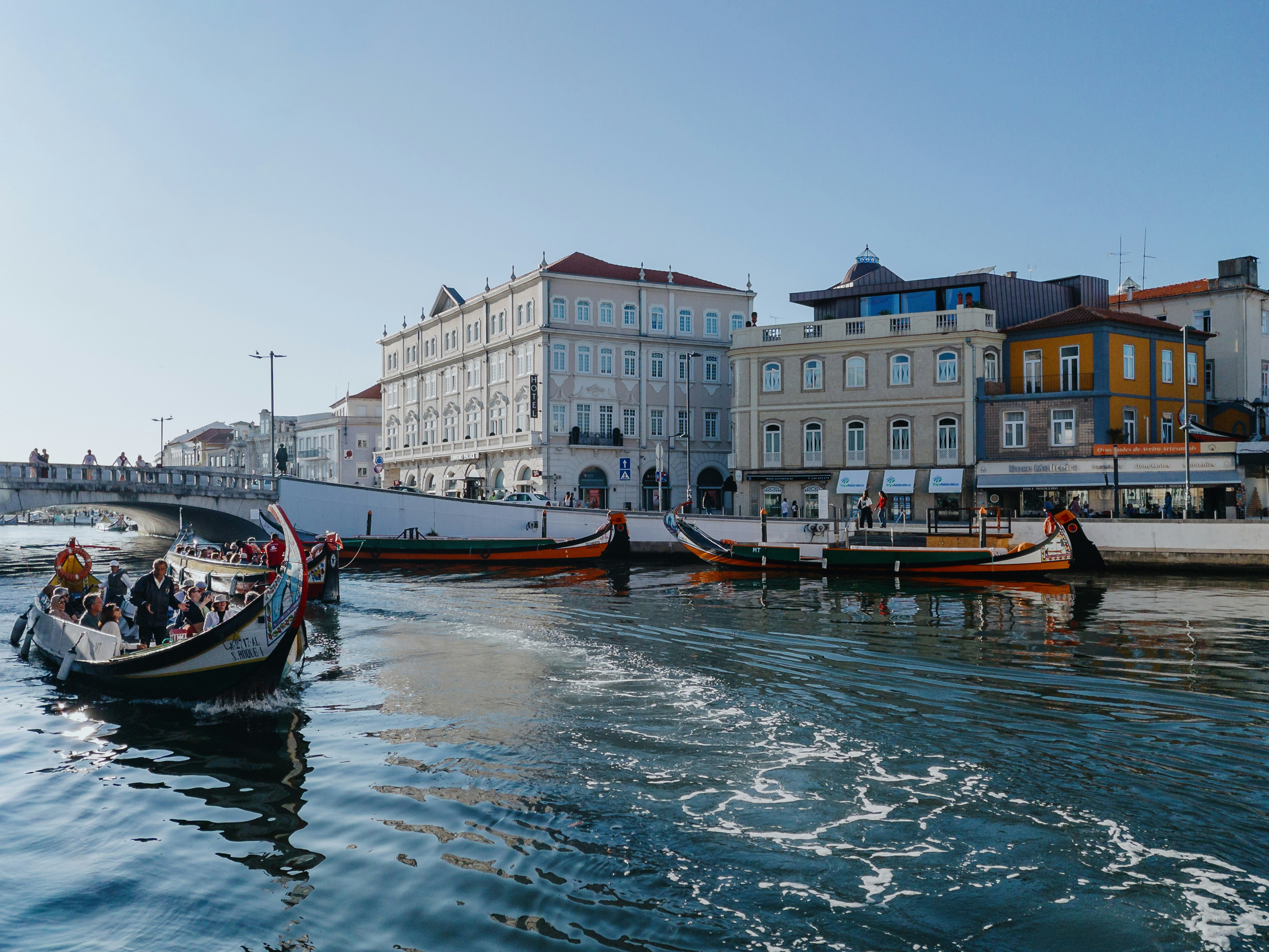 Barche colorate scivolano su un canale passando davanti agli edifici.