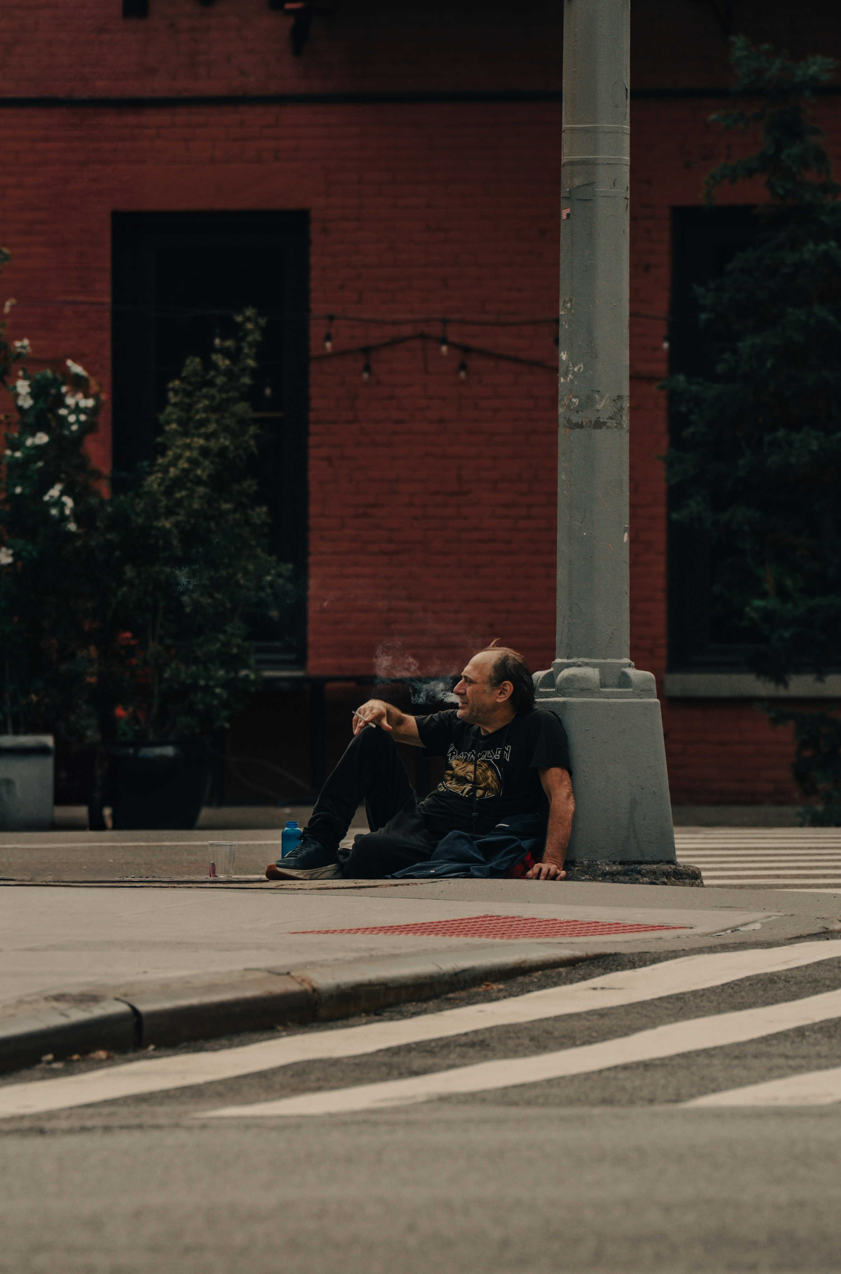 Man sits on sidewalk near brick building