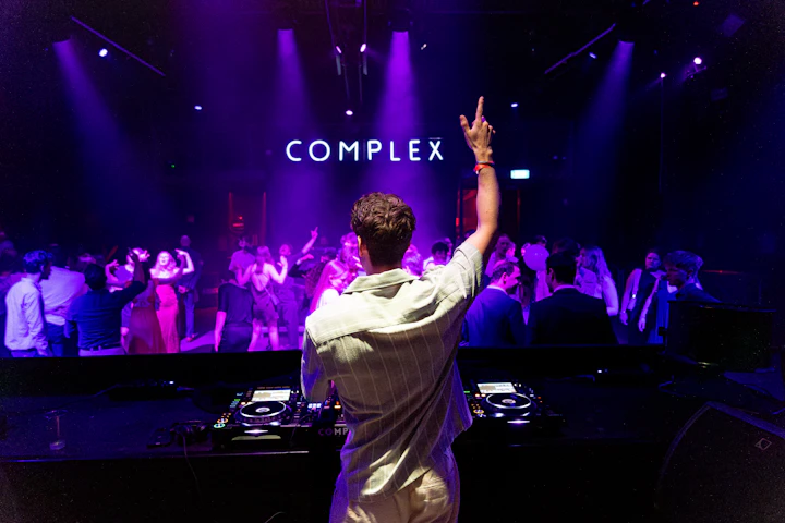 DJ performing for a crowd in a dim nightclub