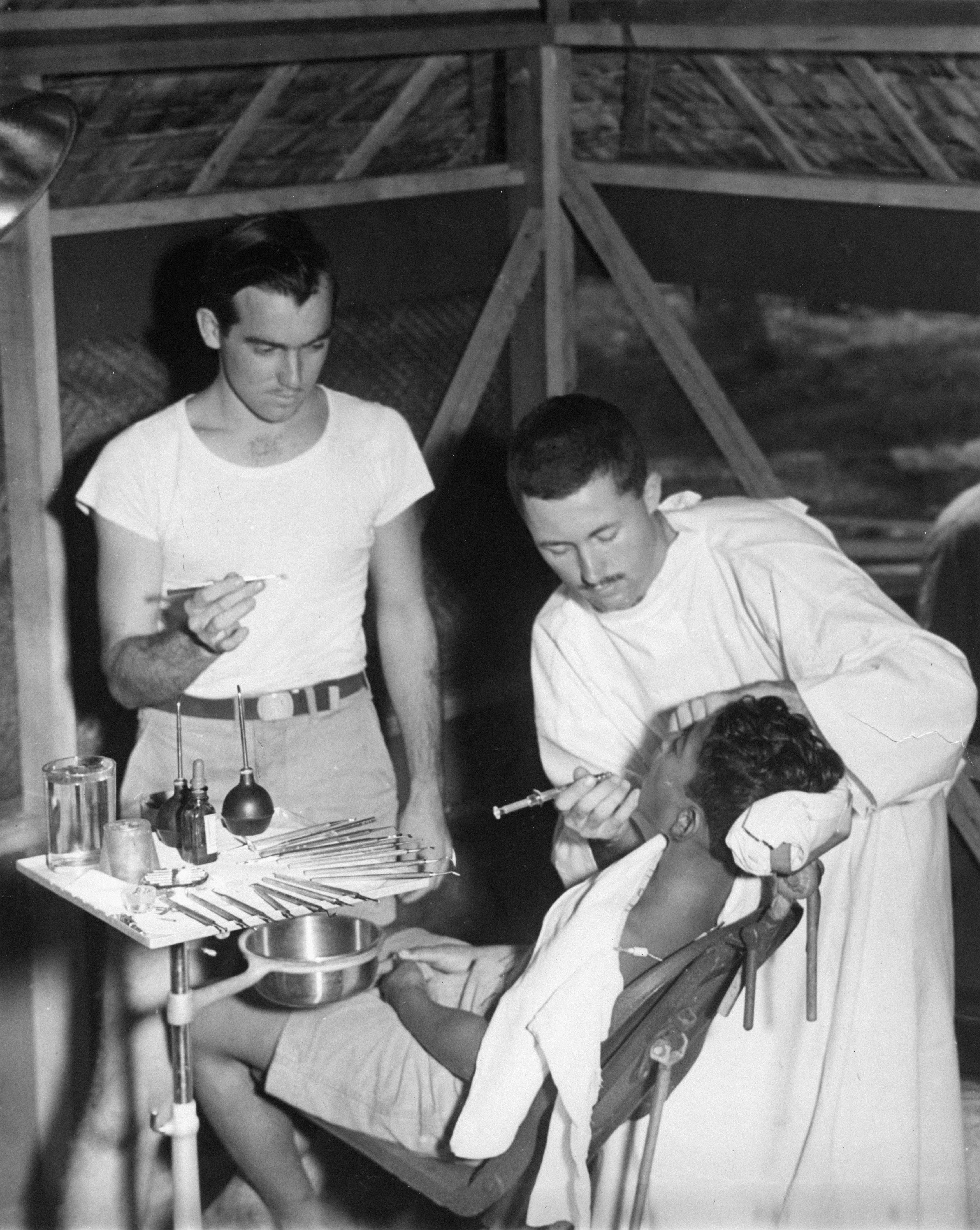 Dentista y asistente tratan al paciente en una clínica improvisada.