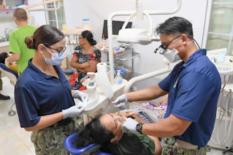 Dentists examine a patient's teeth in a clinic.