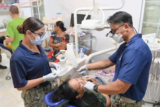 Dentists examine a patient's teeth in a clinic.
