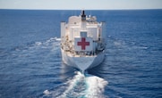 Large hospital ship with red cross sails ocean