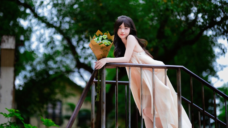Young woman in dress holding bouquet on stairs