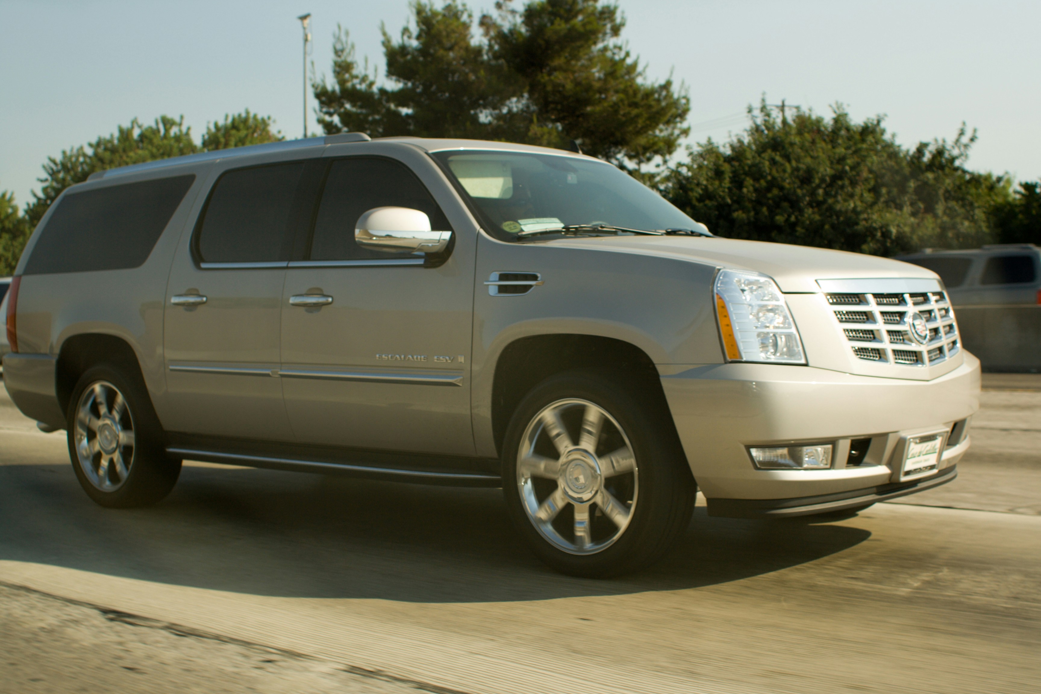 A silver cadillac escalade drives on a highway