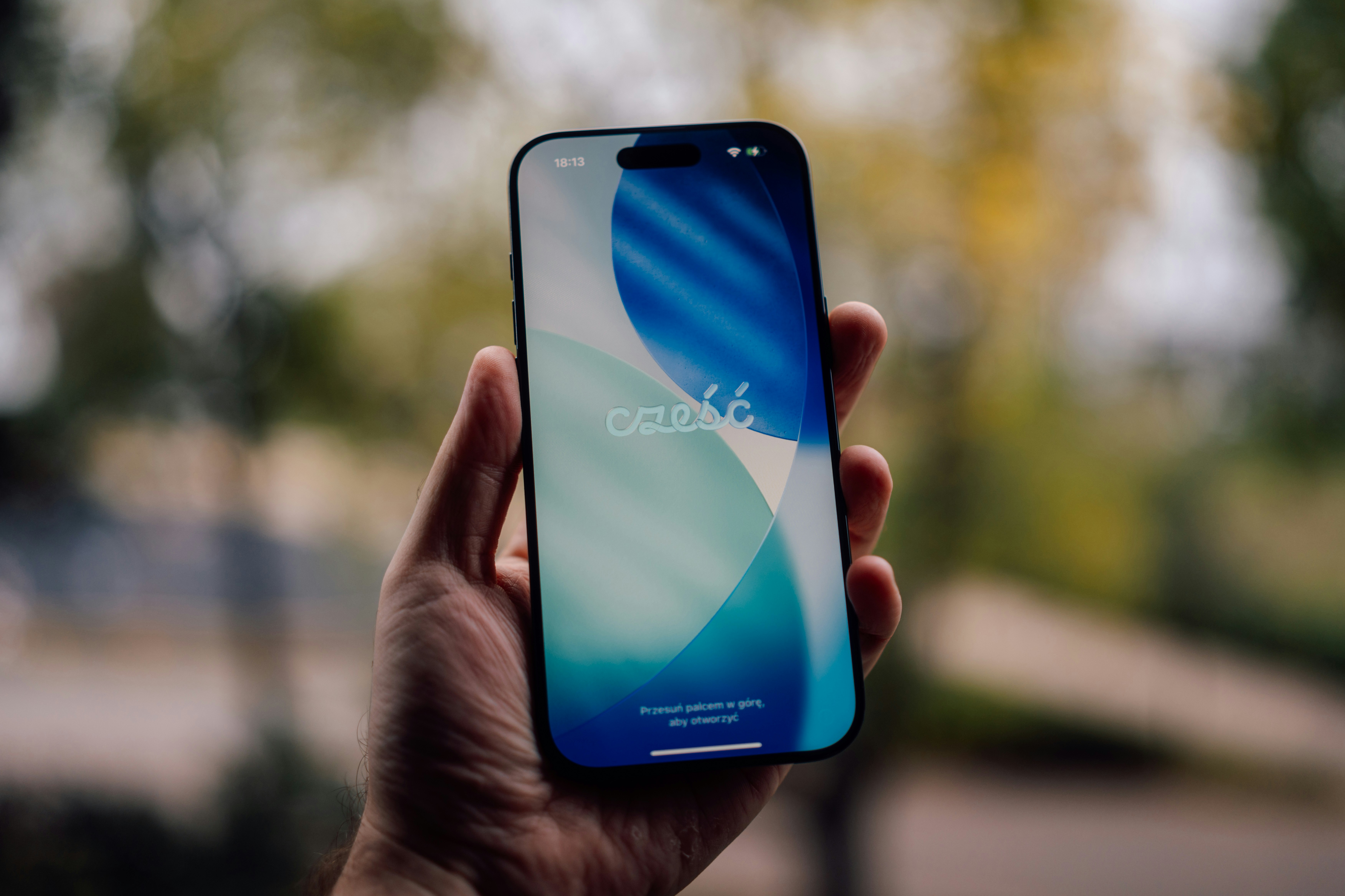 Hand holding a smartphone with a blue and white wallpaper