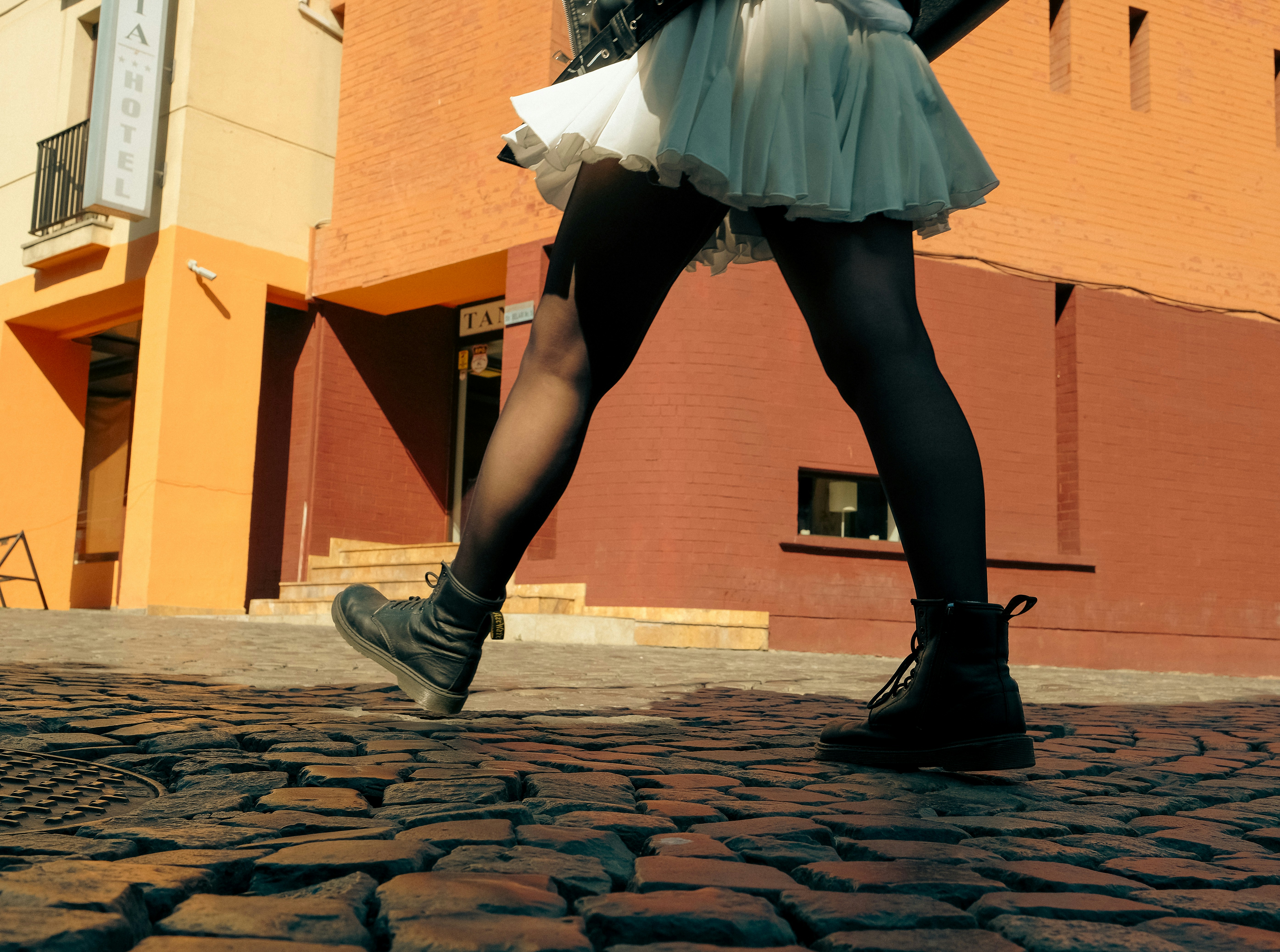 Woman walking on cobblestone street in front of building