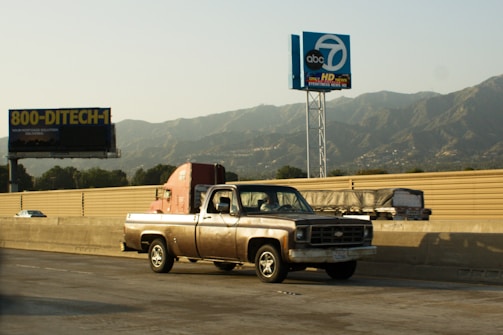 Old pickup truck driving on a highway.