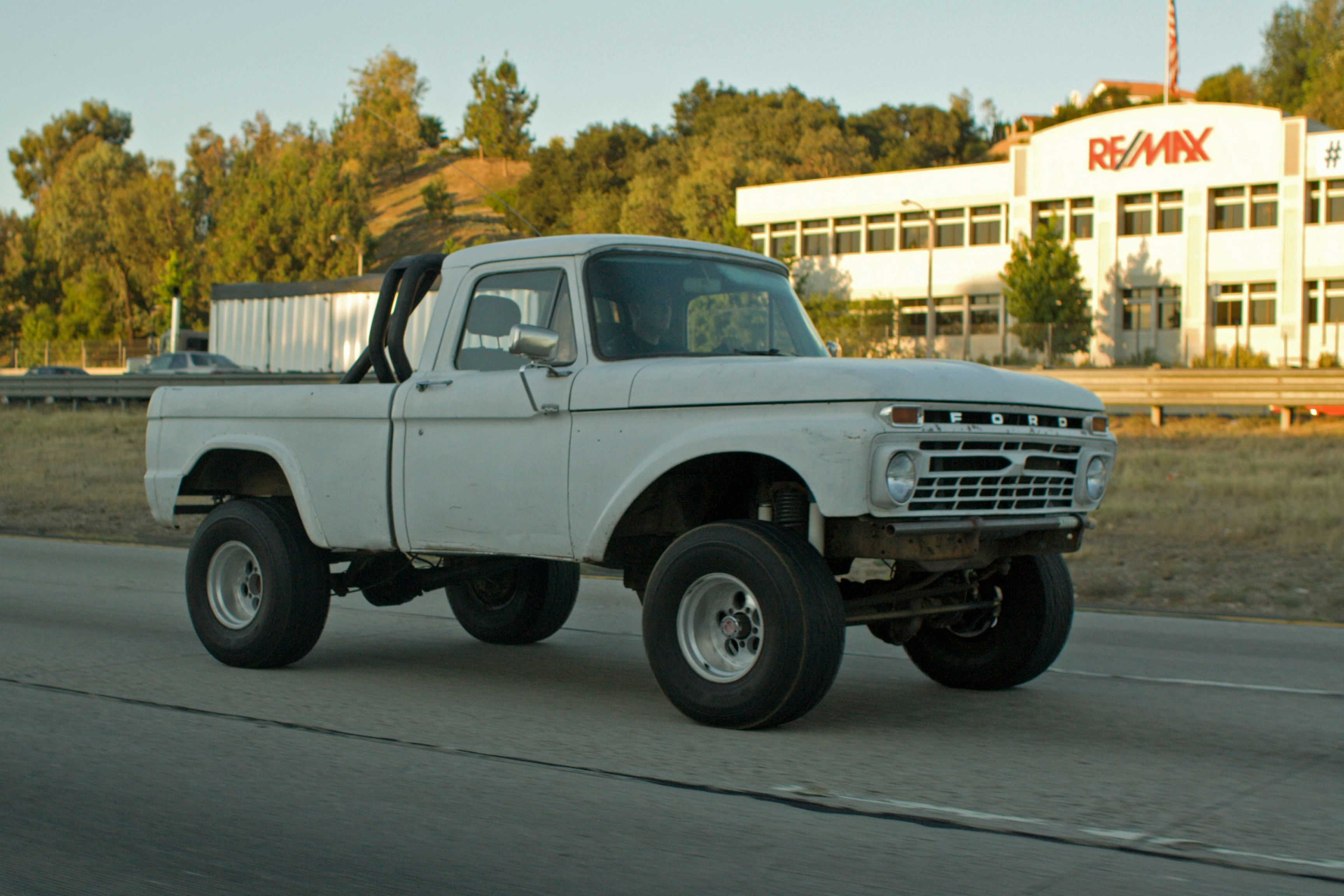 White lifted pickup truck driving on a road.