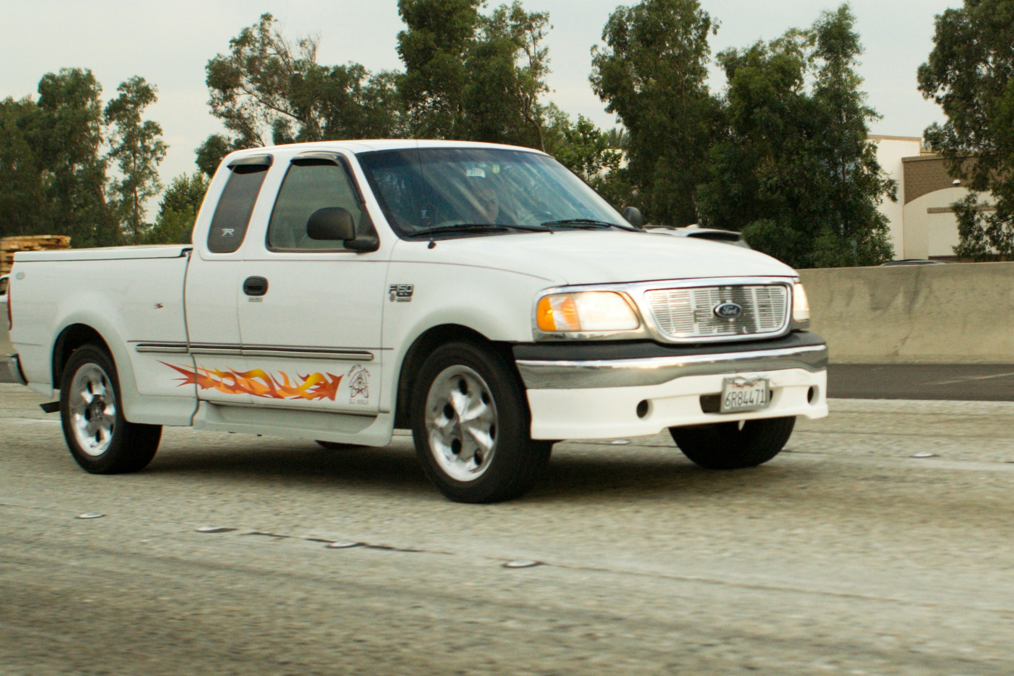White pickup truck driving on a highway.