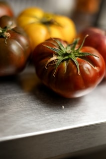 Heirloom tomatoes of various colors on metal surface.