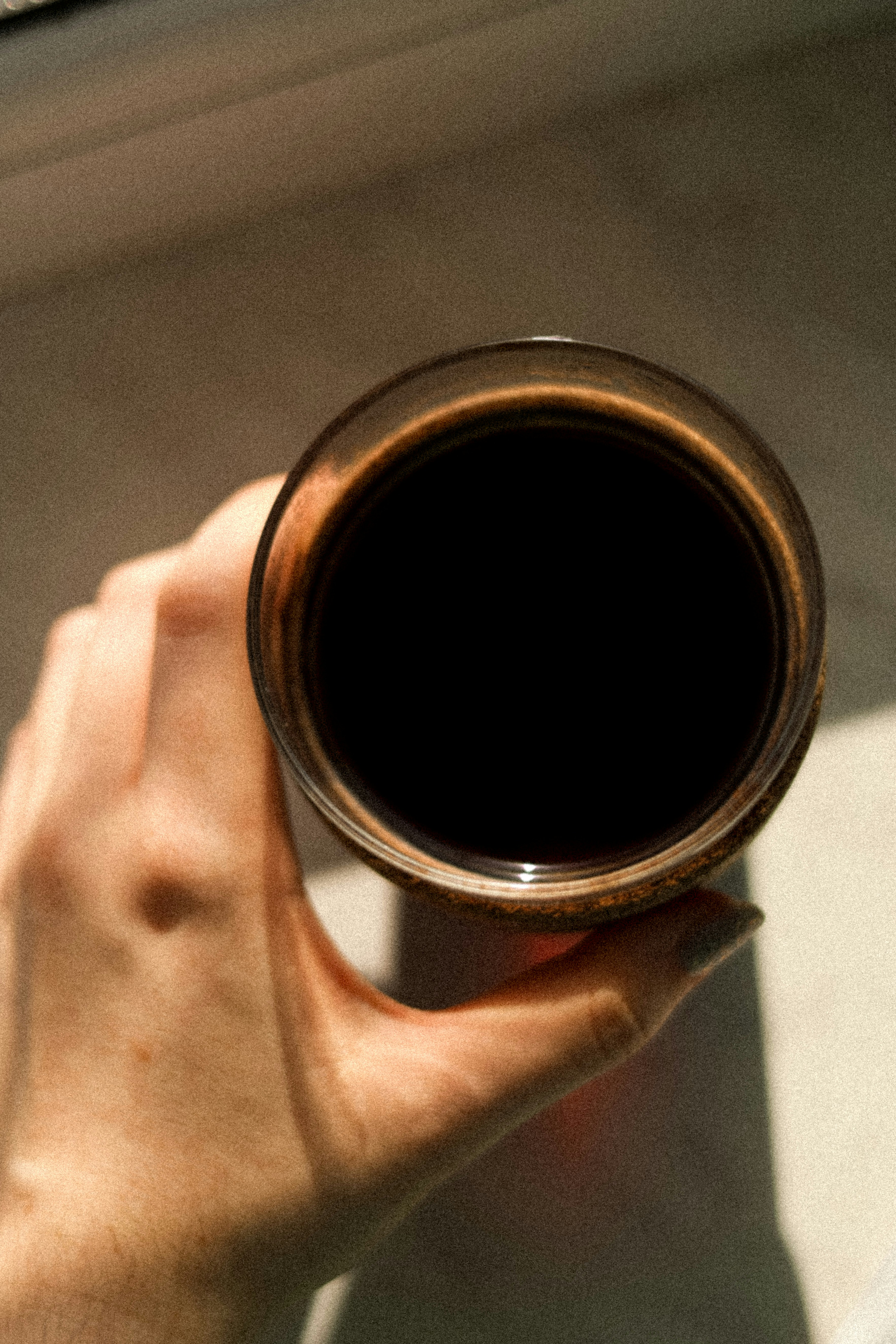Hand holding a glass of dark coffee