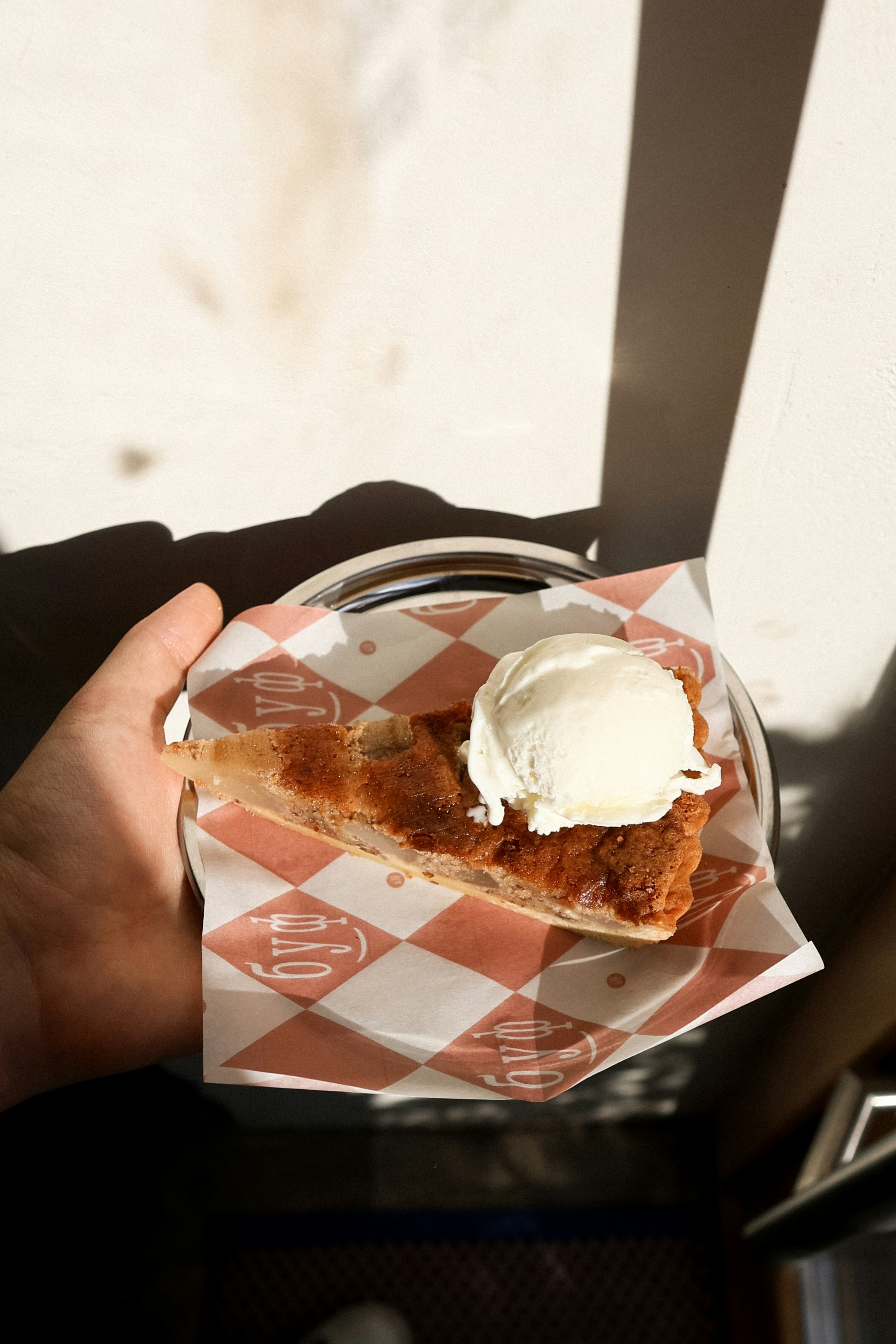 Mão segurando fatia de torta com sorvete