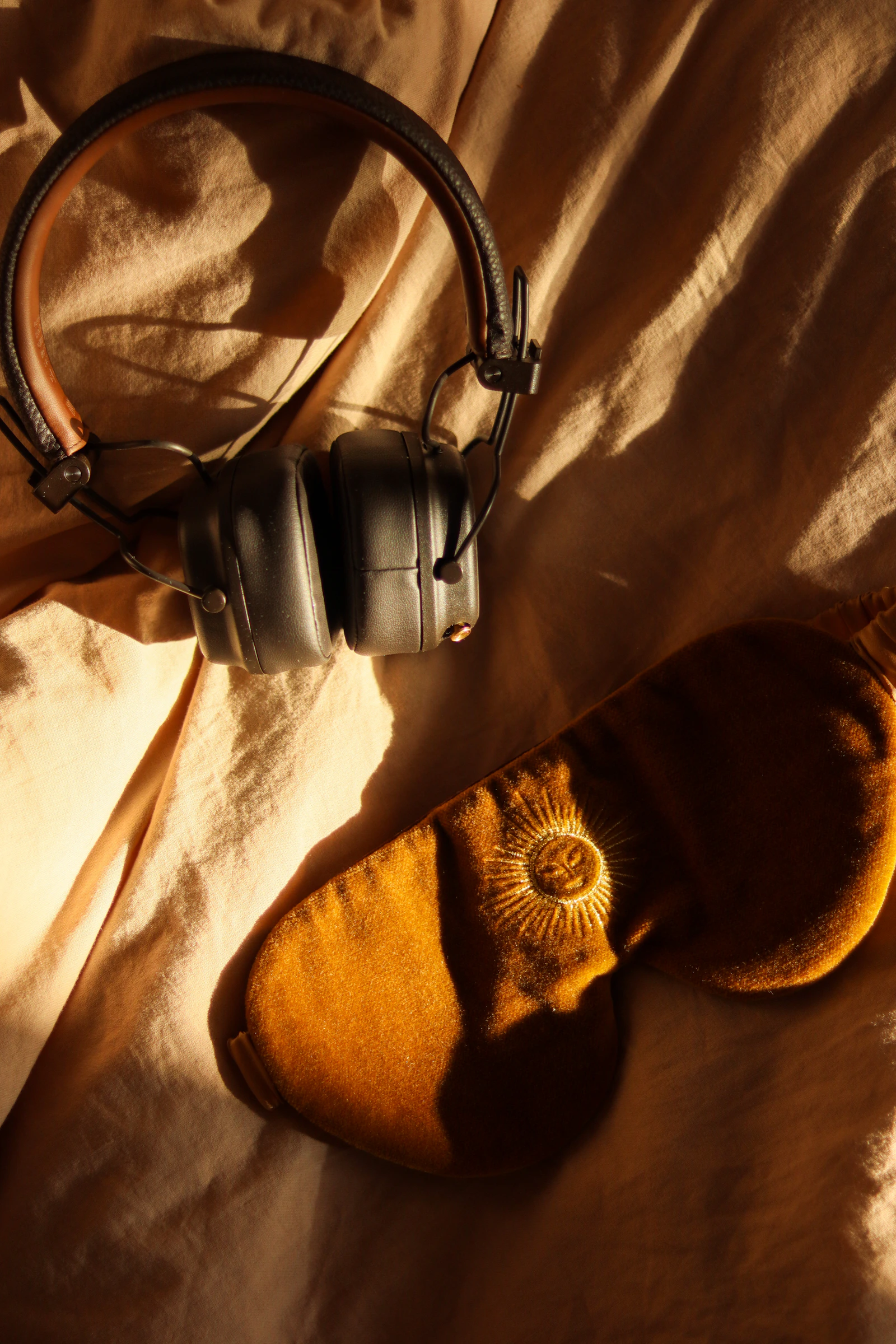 Soft eye mask arranged with travel listening essentials on fabric
