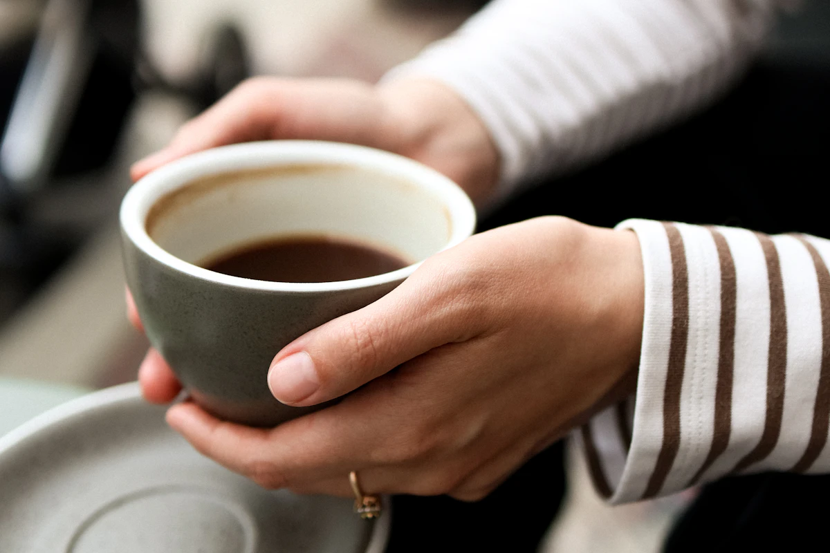 温かいコーヒーカップを両手で包む