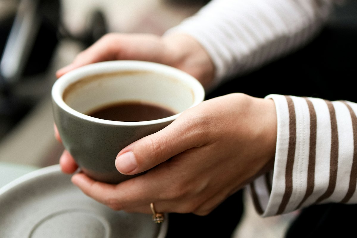 Manos sosteniendo una taza de café caliente en temporada fría
