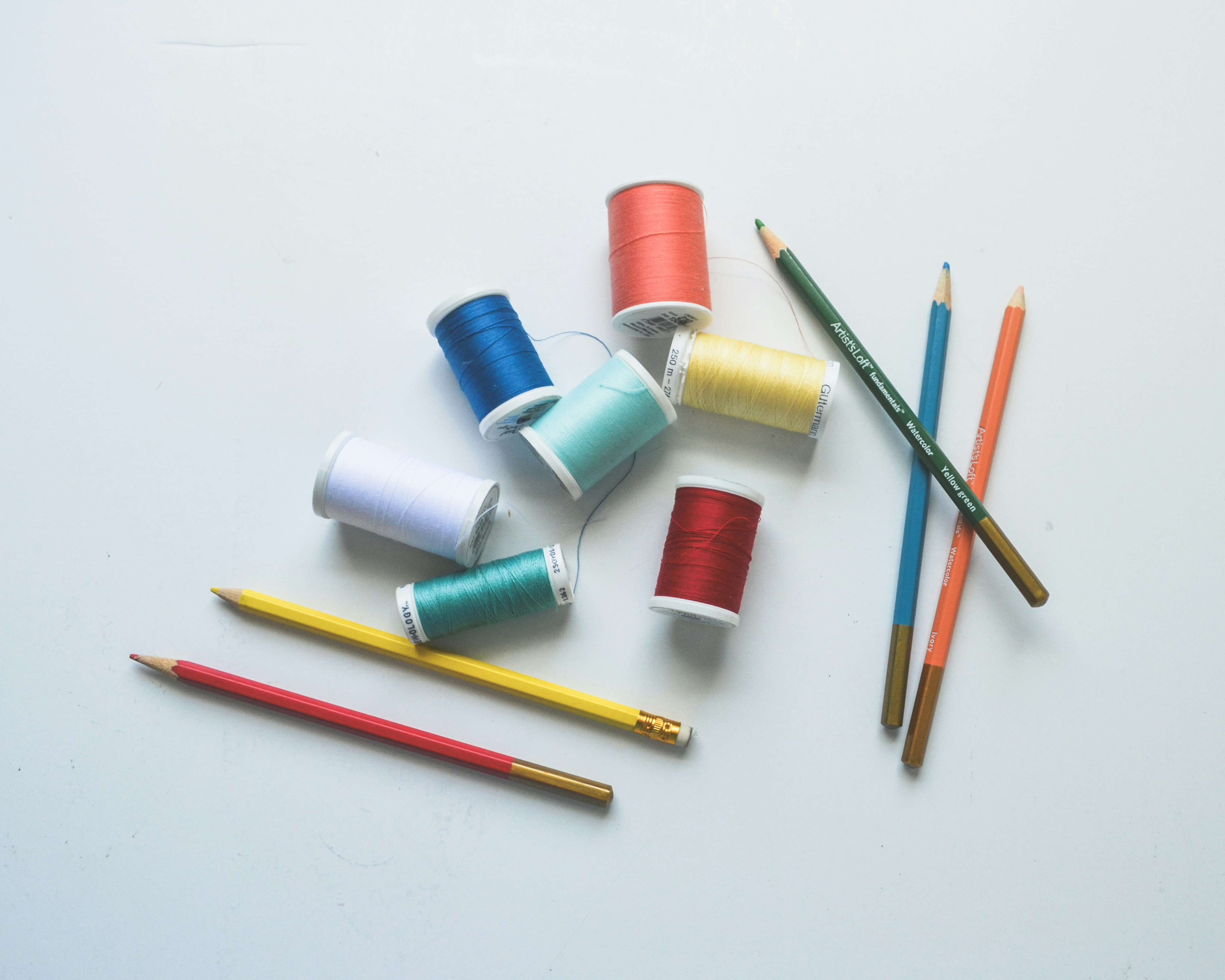 Thread spools and colored pencils arranged creatively