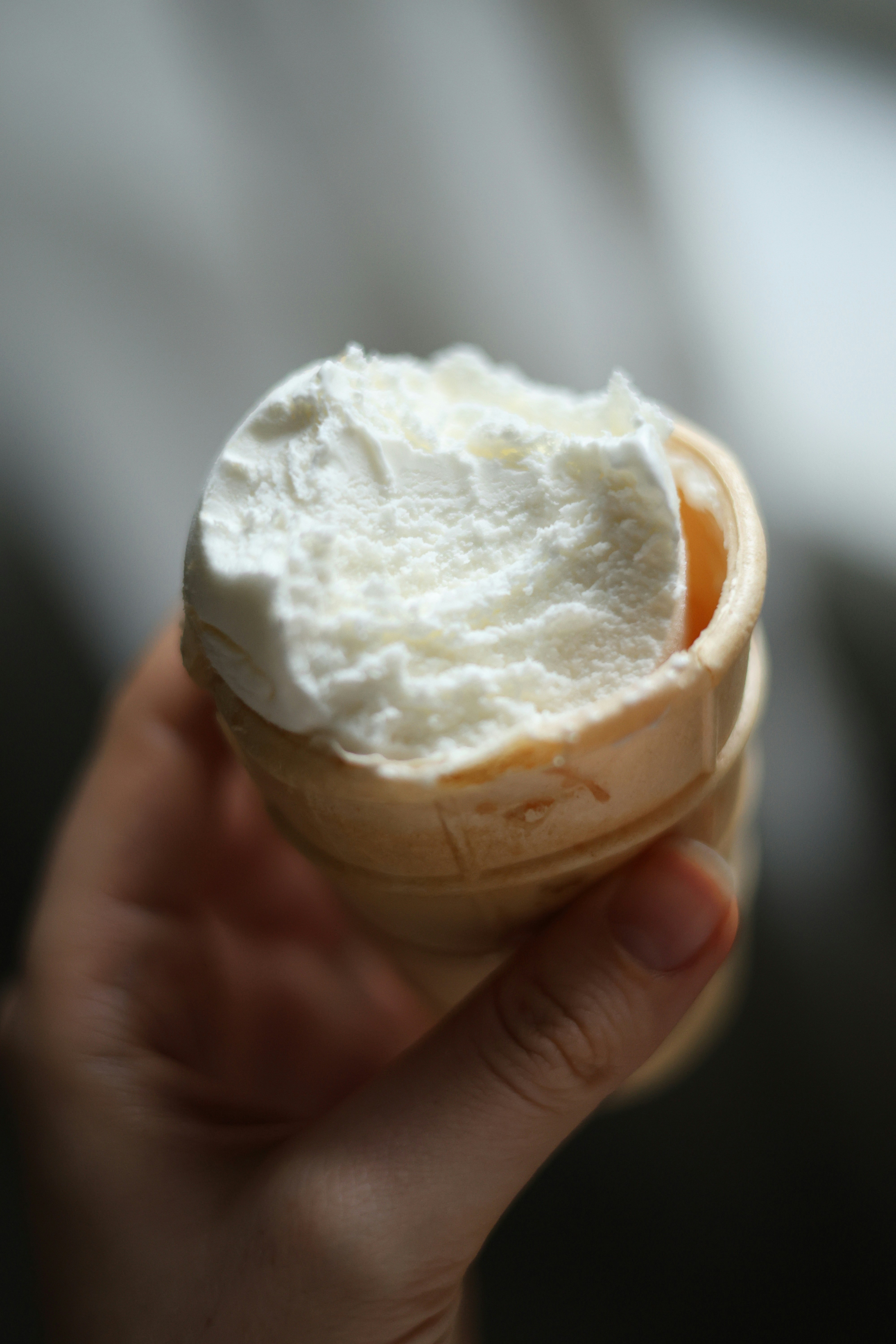 Hand holding a vanilla ice cream cone