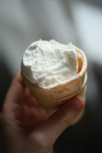 Hand holding a vanilla ice cream cone