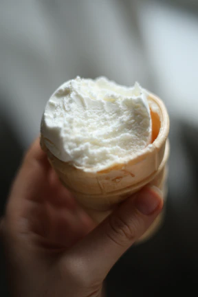 Hand holding a vanilla ice cream cone