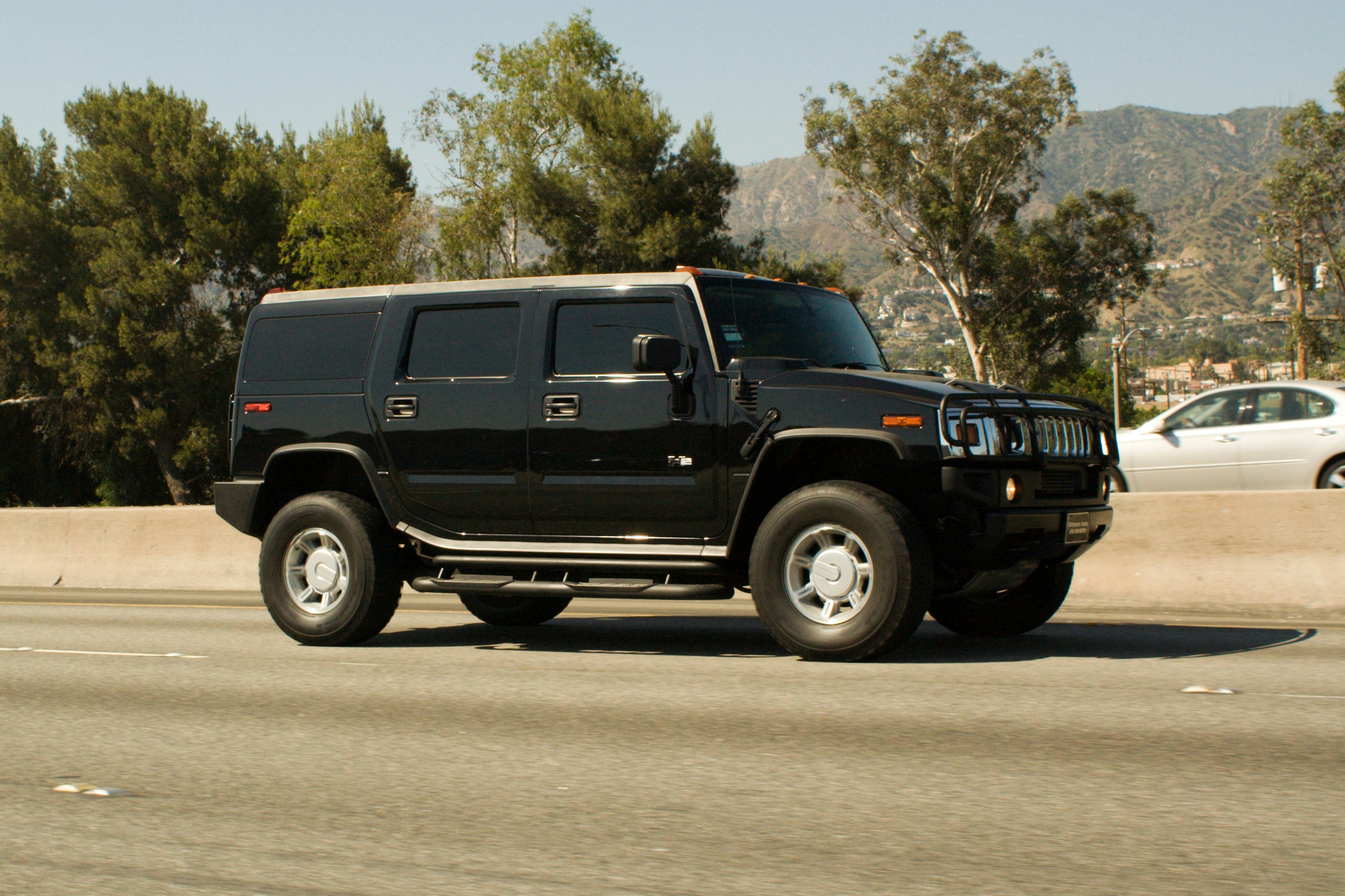 Black hummer h2 driving on a highway.