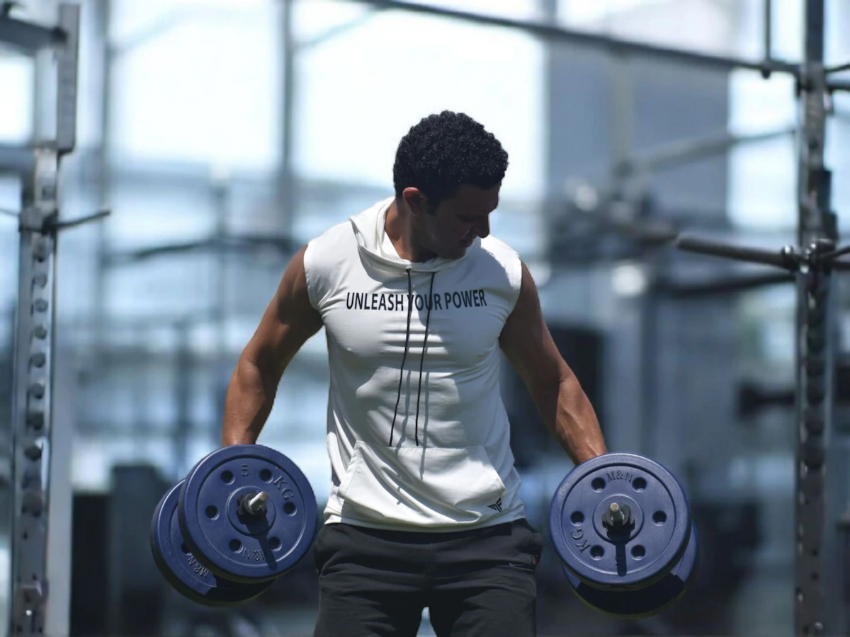 Male athlete carrying dumbbells in a bright modern training gym