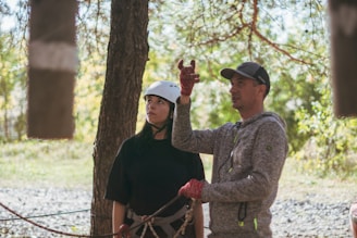 Instructor guiding a young woman in outdoor adventure activity.