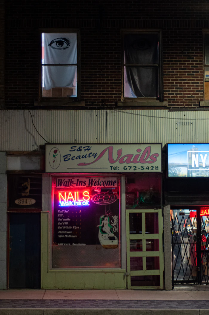 Nail salon storefront with a neon sign in the window