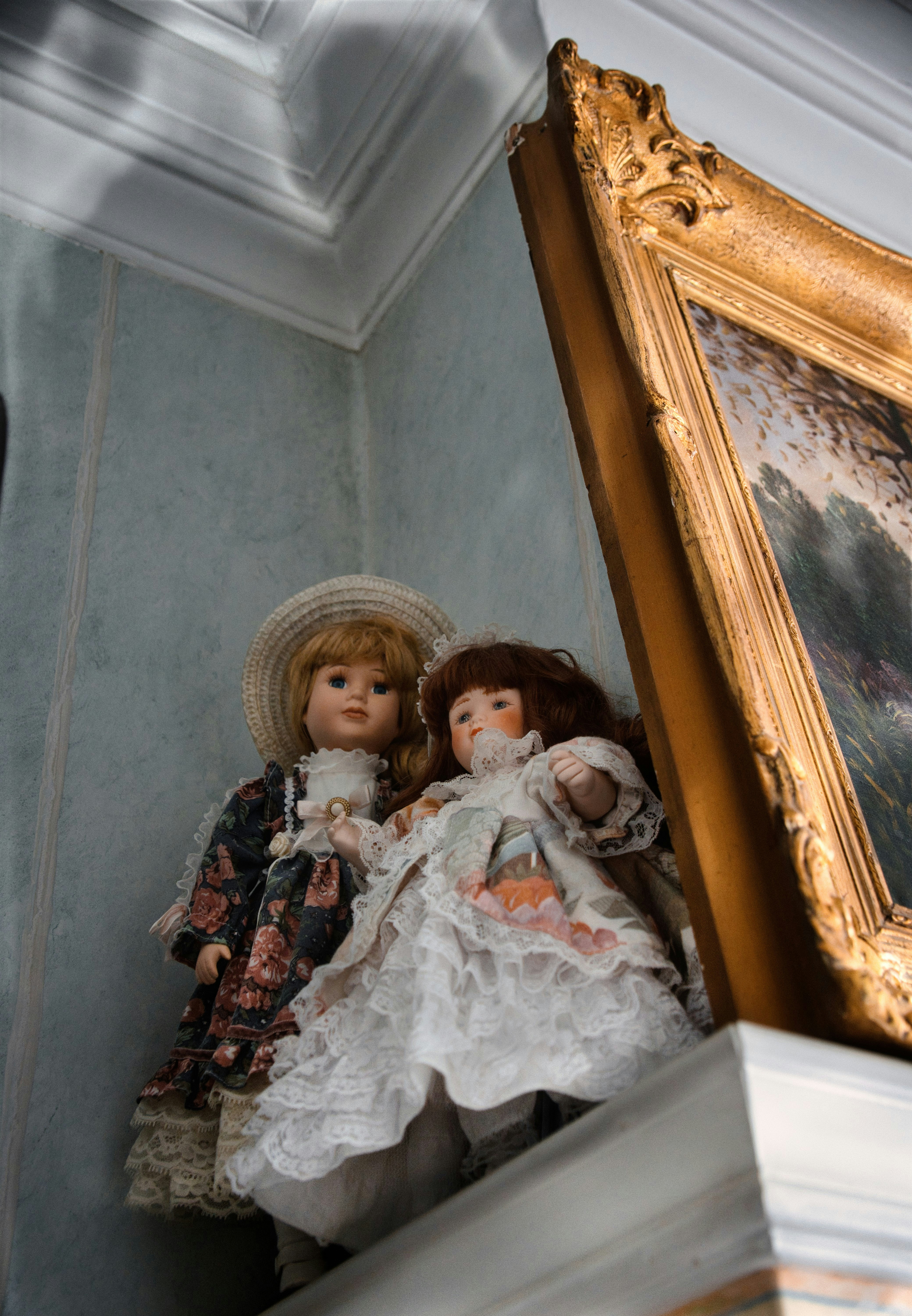 Two antique dolls in ornate dresses and vintage dresses.