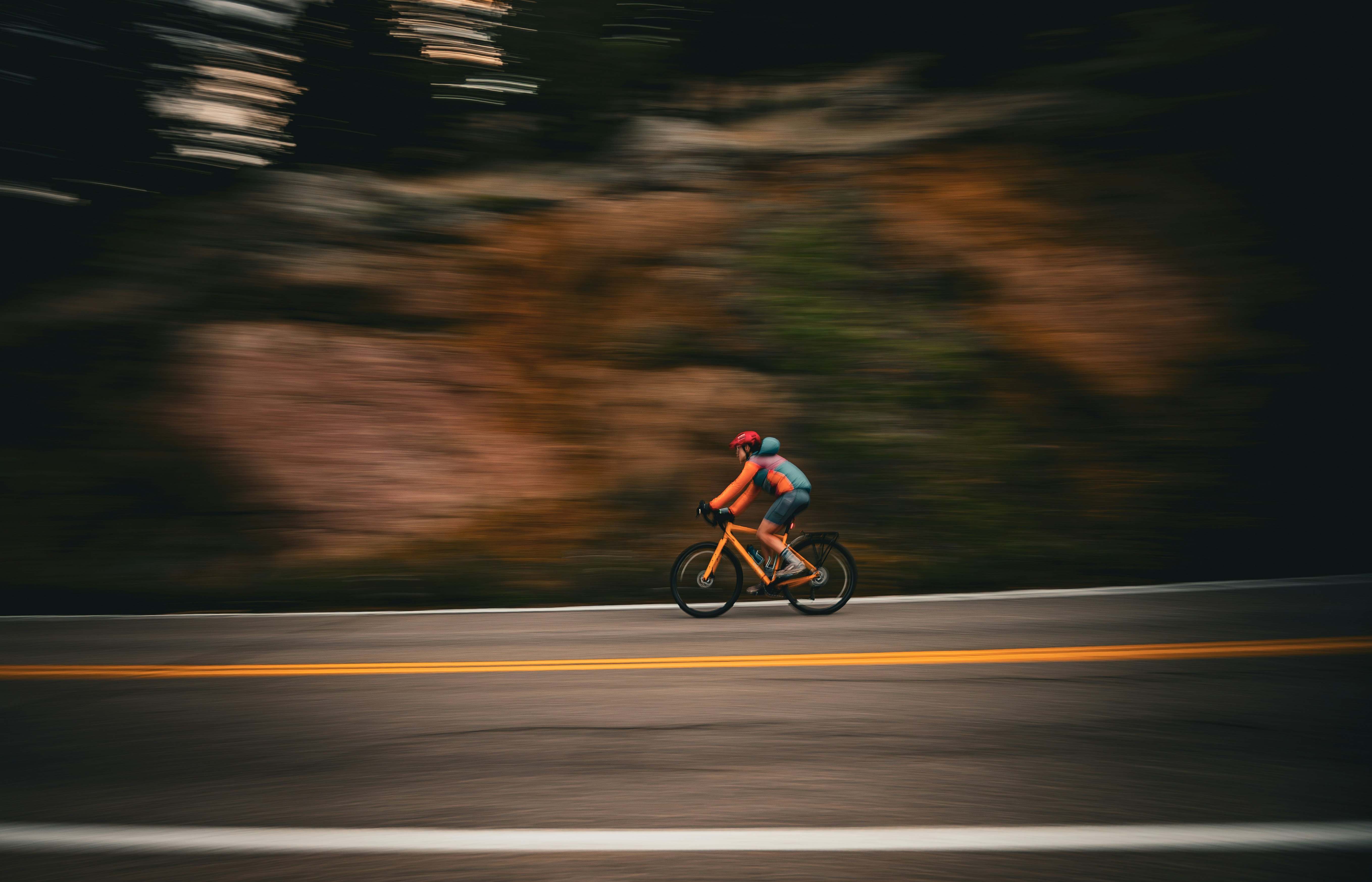 Cyclist rides on a road with blurred background.