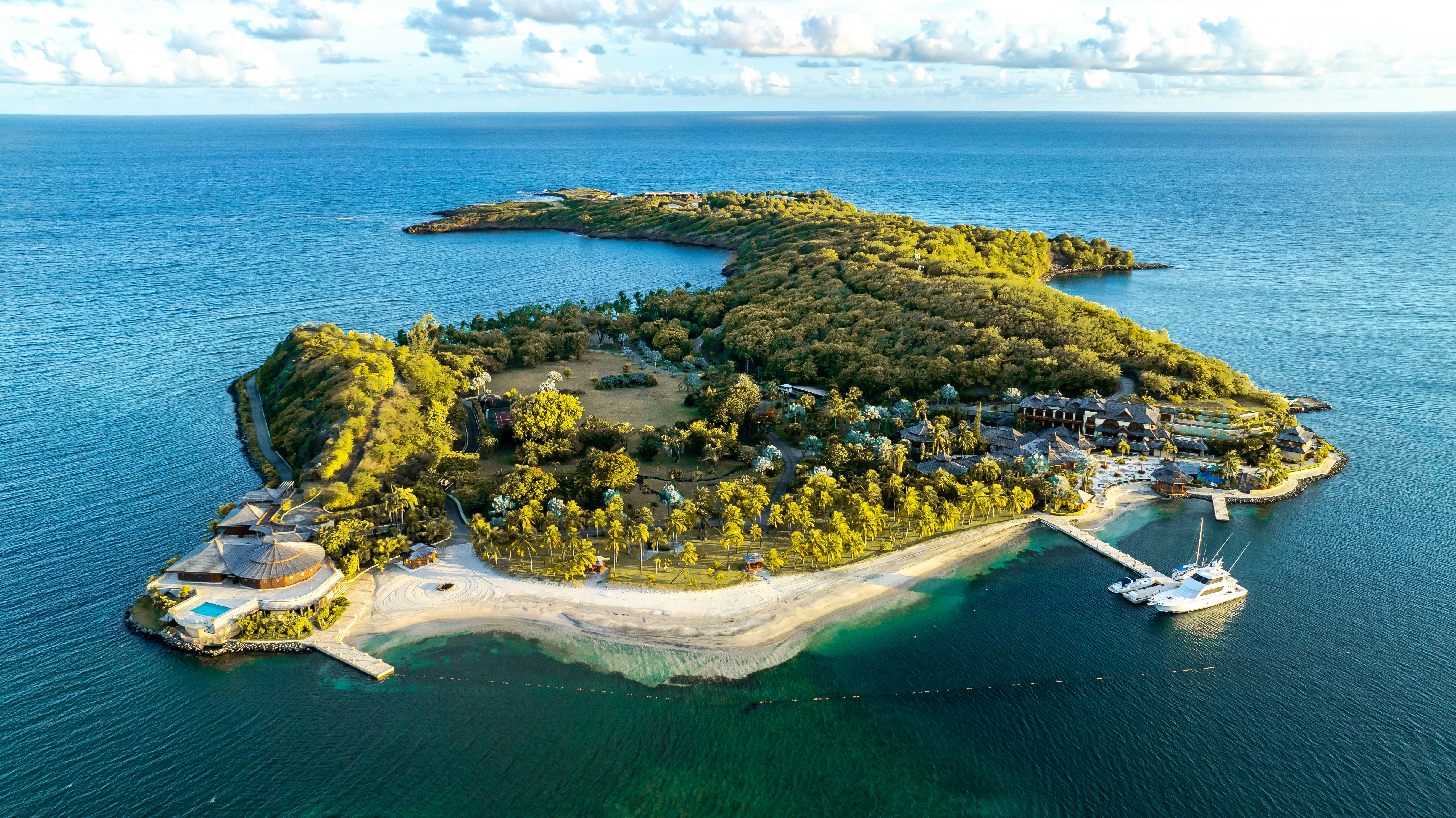 Lush green island resort surrounded by clear blue ocean water.