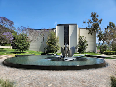 Modern building with a circular water feature and sculpture.