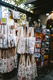 Souvenir tote bags and tins displayed at a market stall.