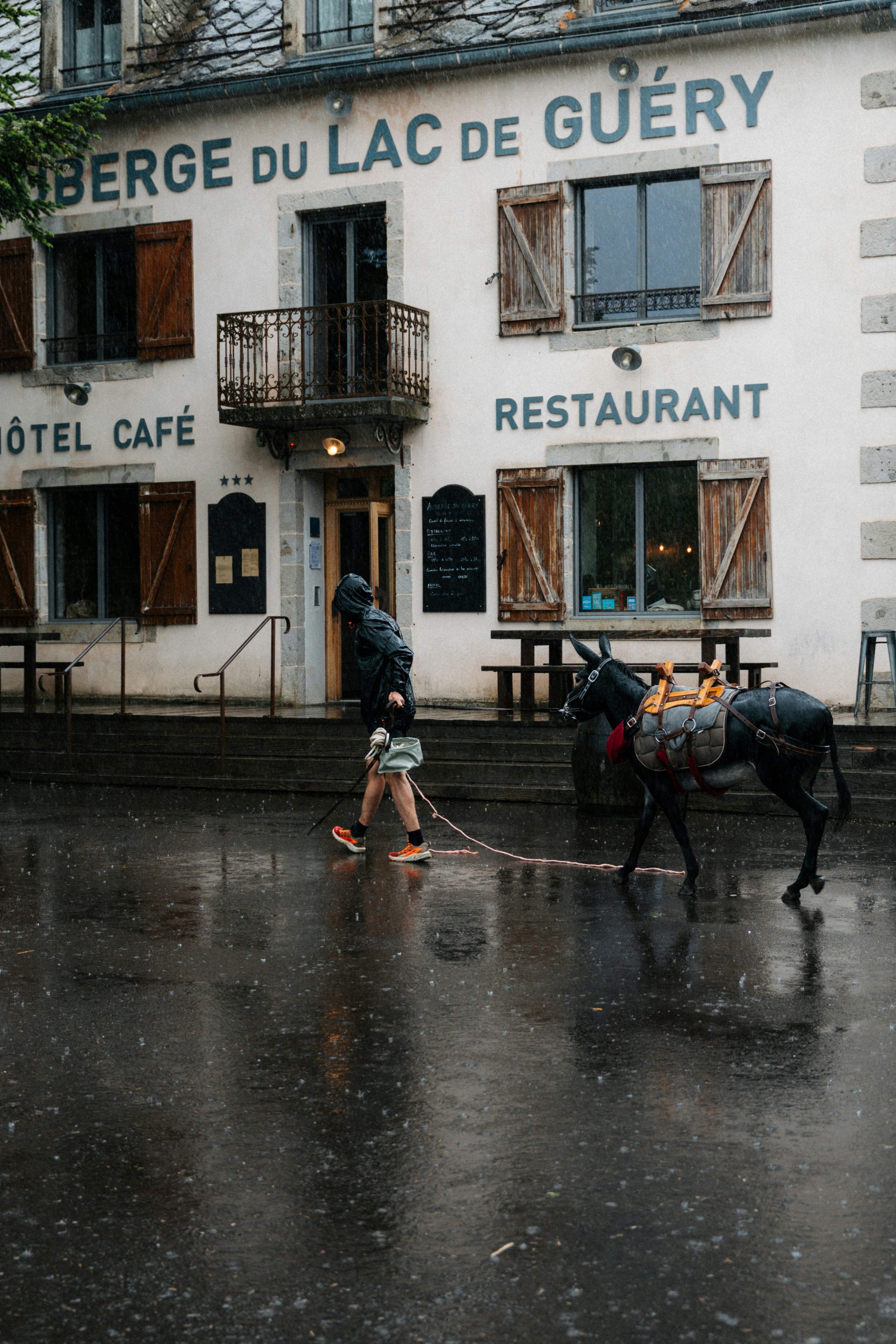 Hombre pasea burro bajo la lluvia fuera del restaurante.