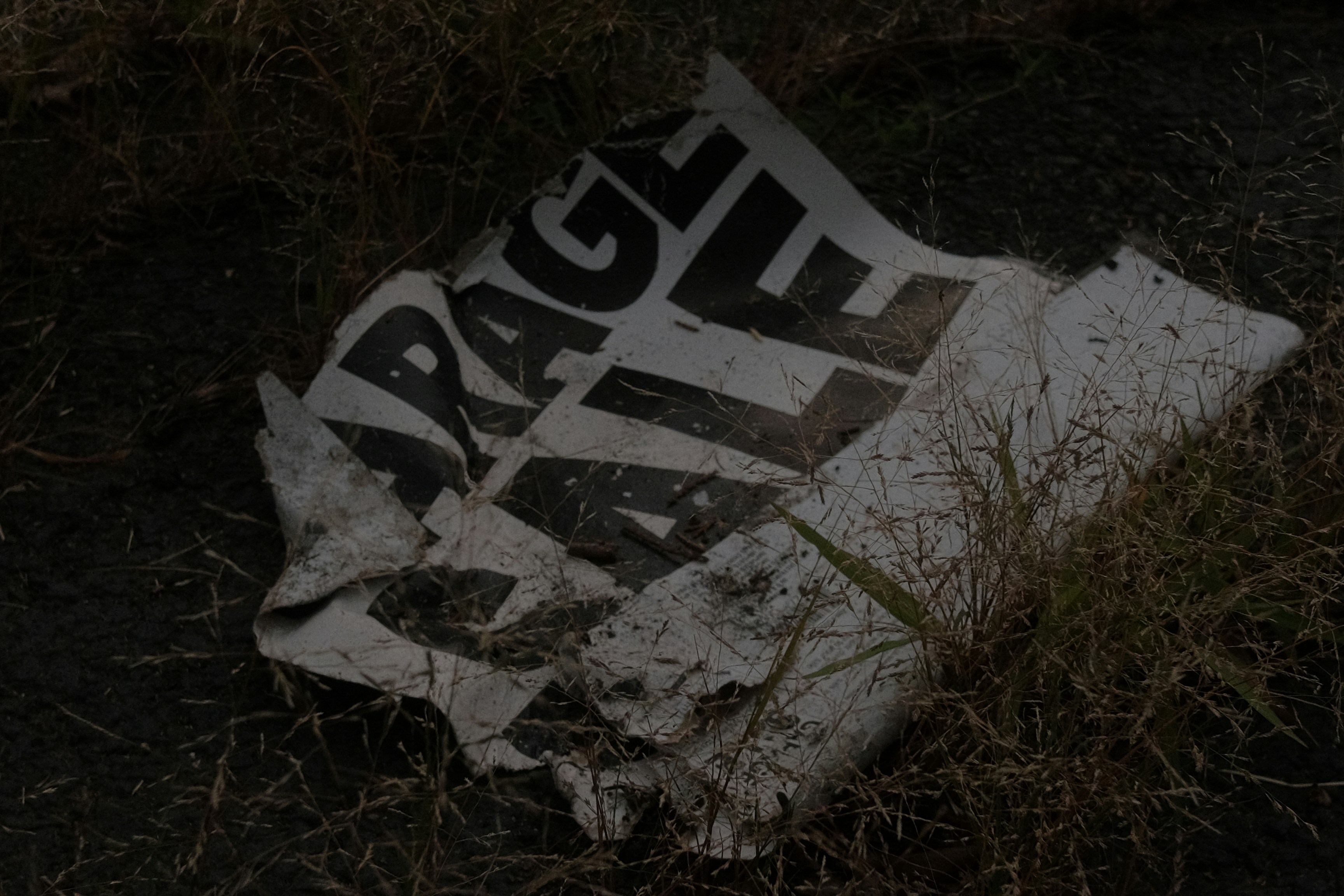Crumpled "rage sale" sign lying on the ground