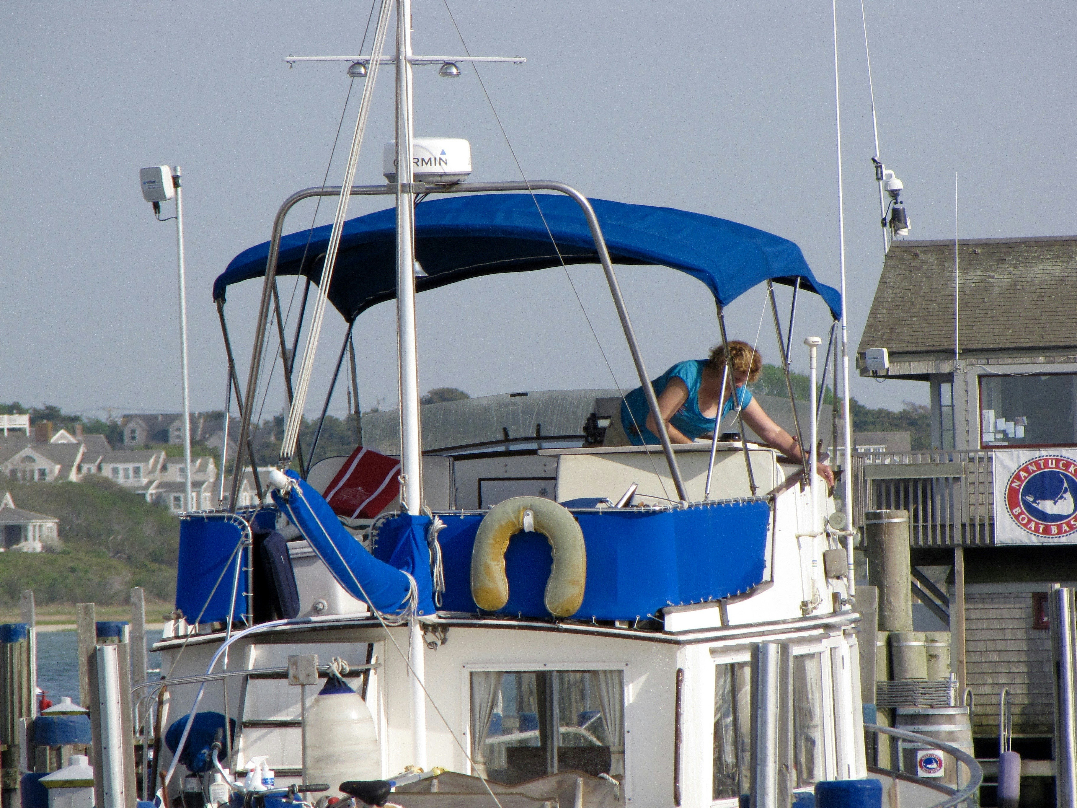 Woman on a boat adjusting a blue canopy.