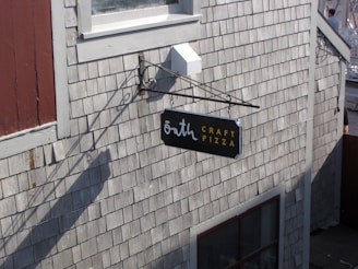 Sign for "bath craft pizza" on shingled wall