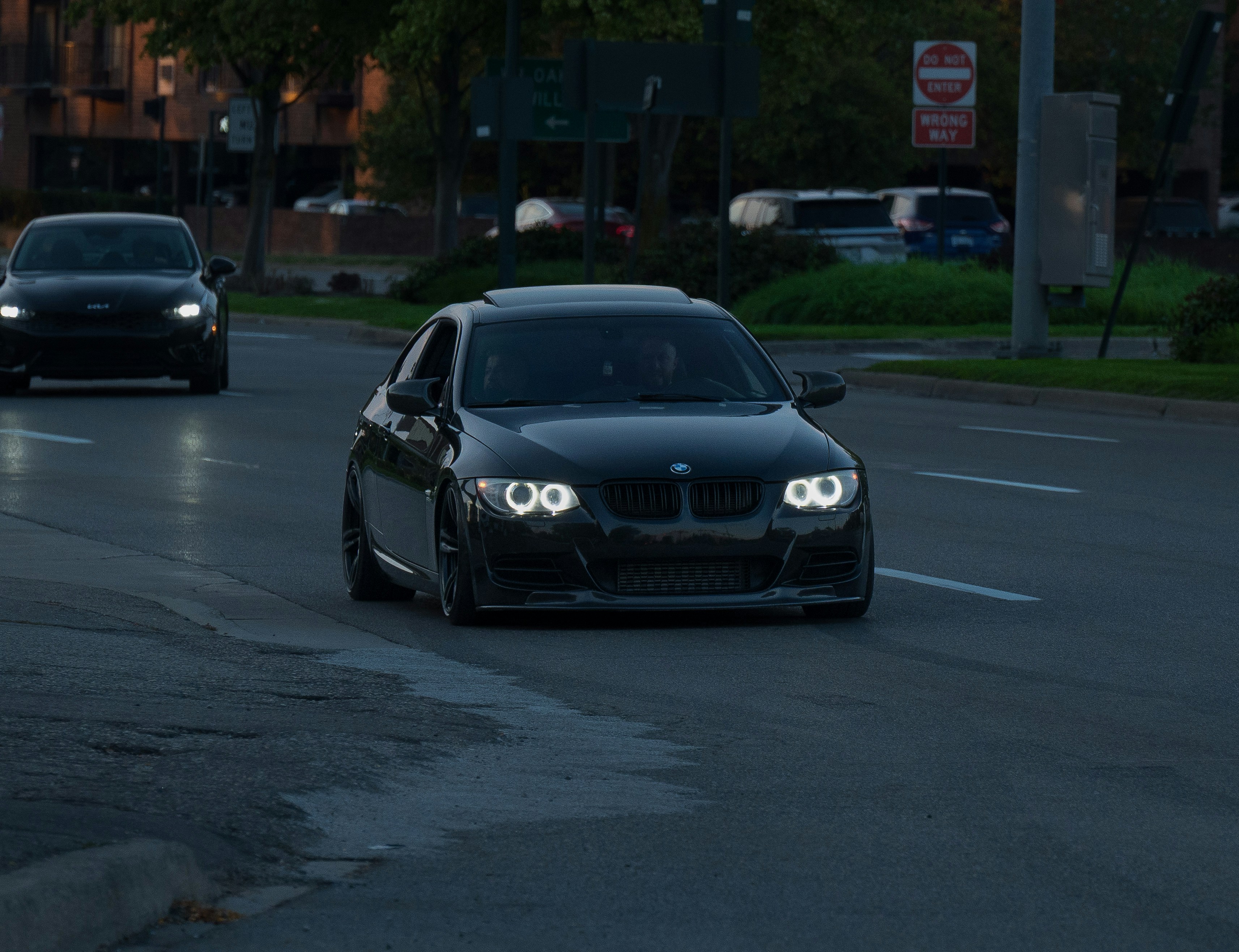 A black sports car driving on a city street.