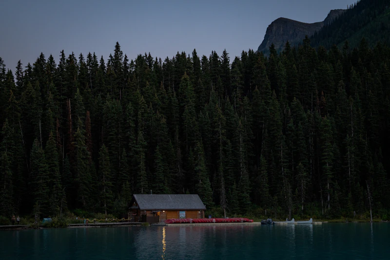 Wooden cabin by a serene lake with forest backdrop