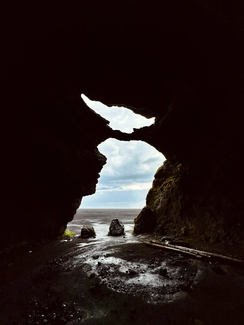 View through cave opening to rocky ocean beach