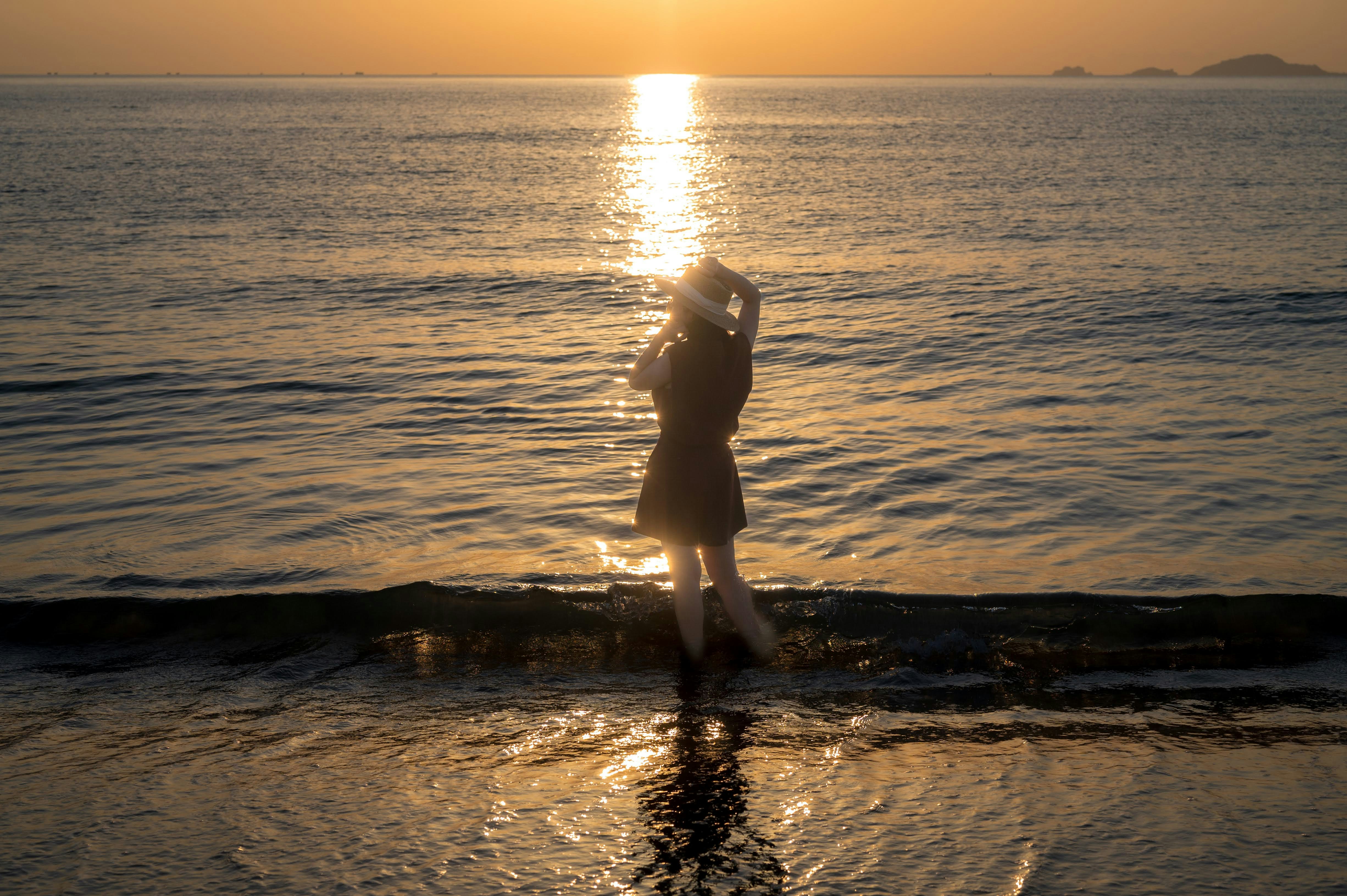 Woman standing on shore at sunset